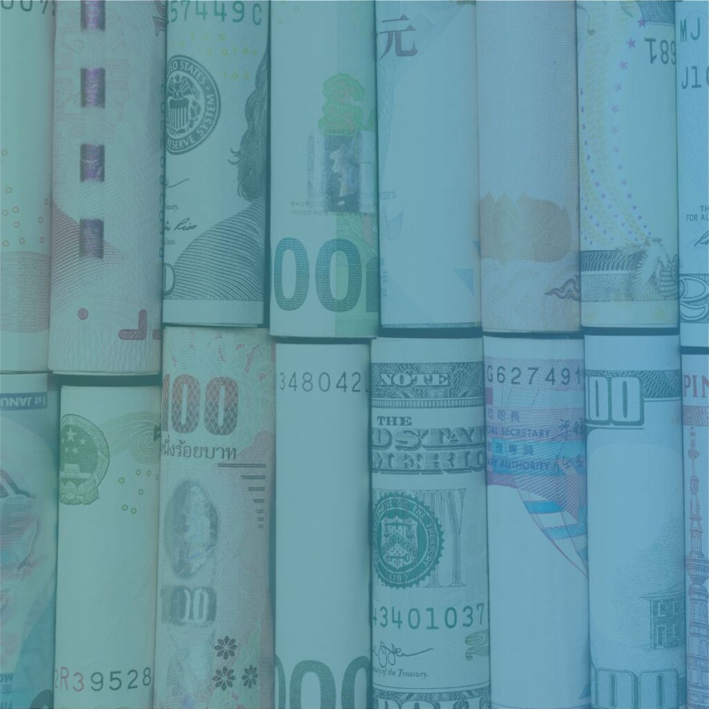 Rolled banknotes from different countries representing international invoicing and global payroll for recruitment agencies.