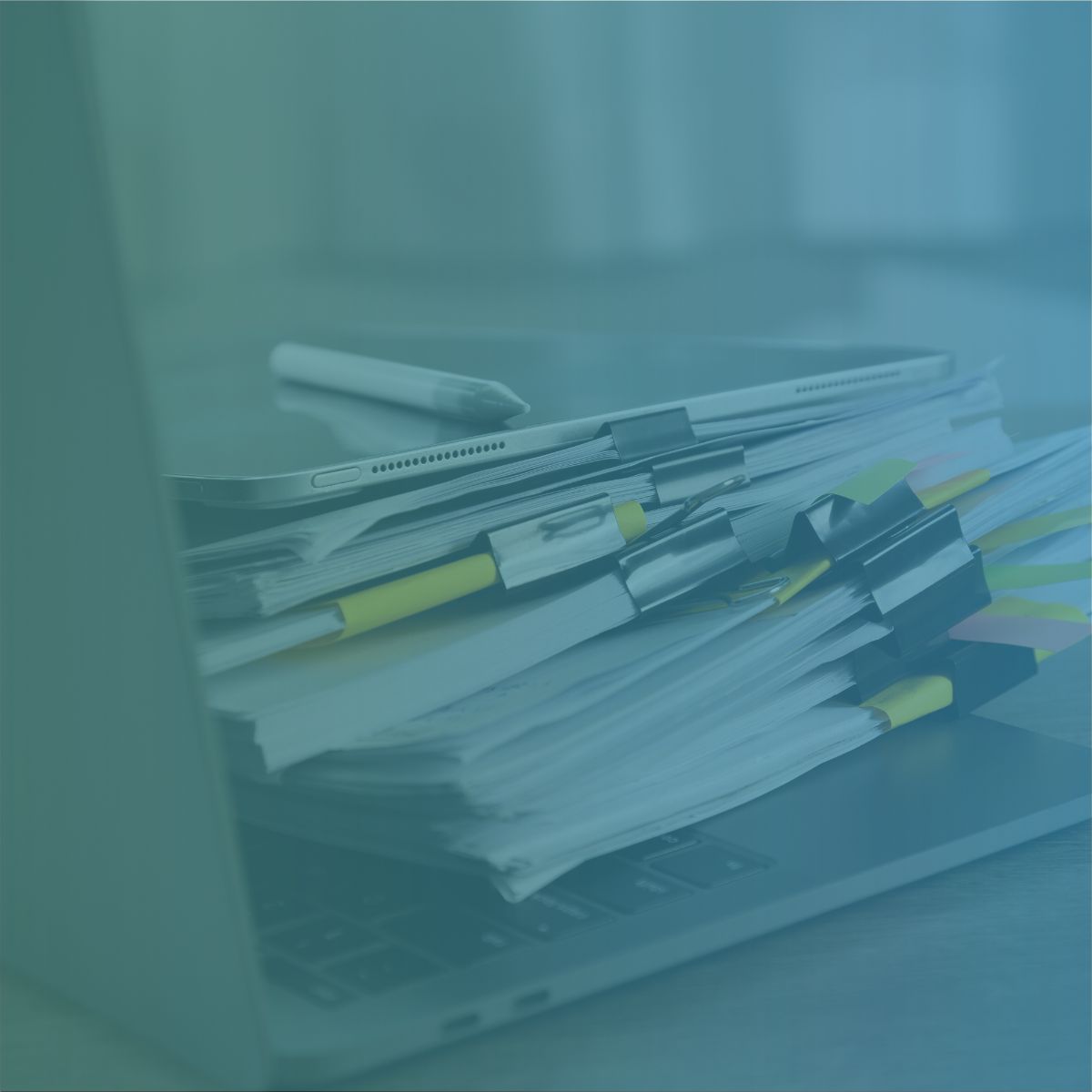 A messy stack of paper contractor timesheets piled on a laptop keyboard representing manual vs digital recruitment back-office processes.